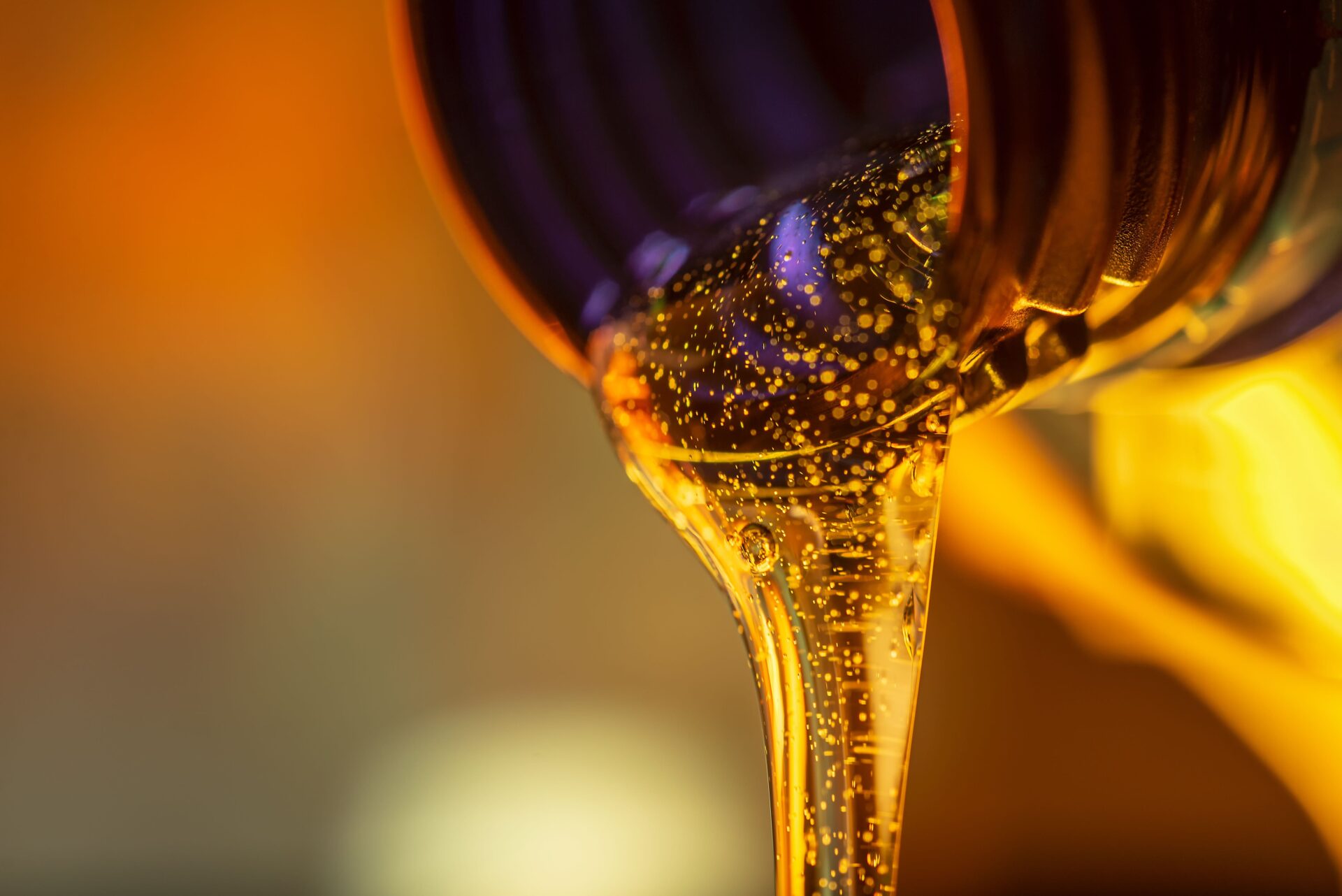 Liquid stream of motorcycle motor oil flows from the neck of the bottle close-up. Liquid stream of motorcycle motor oil flows from the neck of the bottle close-up.